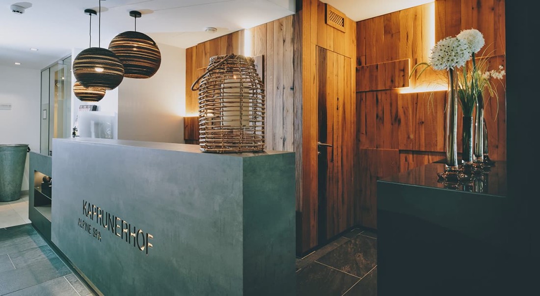 Empfangsbereich vom Spa mit modernen Lampen und Holzverkleidung im im Wellnesshotel Kaprunerhof