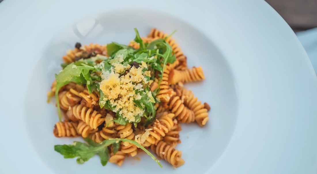 Pasta mit Rucola und Parmesan auf einem wei&szlig;en Teller
