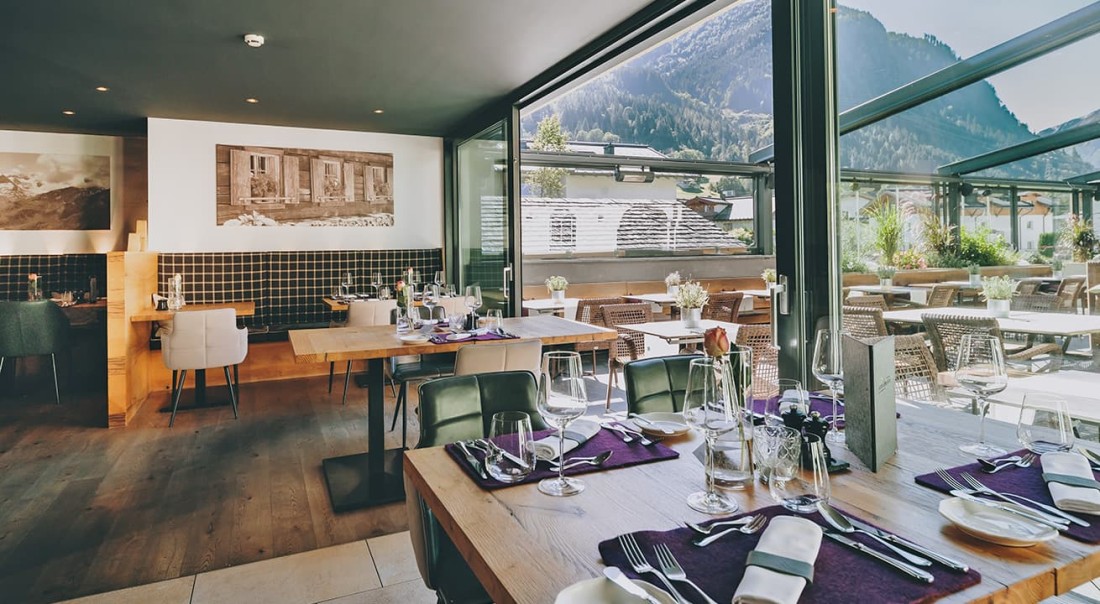 Modernes Restaurant mit Bergblick und gedeckten Tischen im Hotel Kaprunerhof