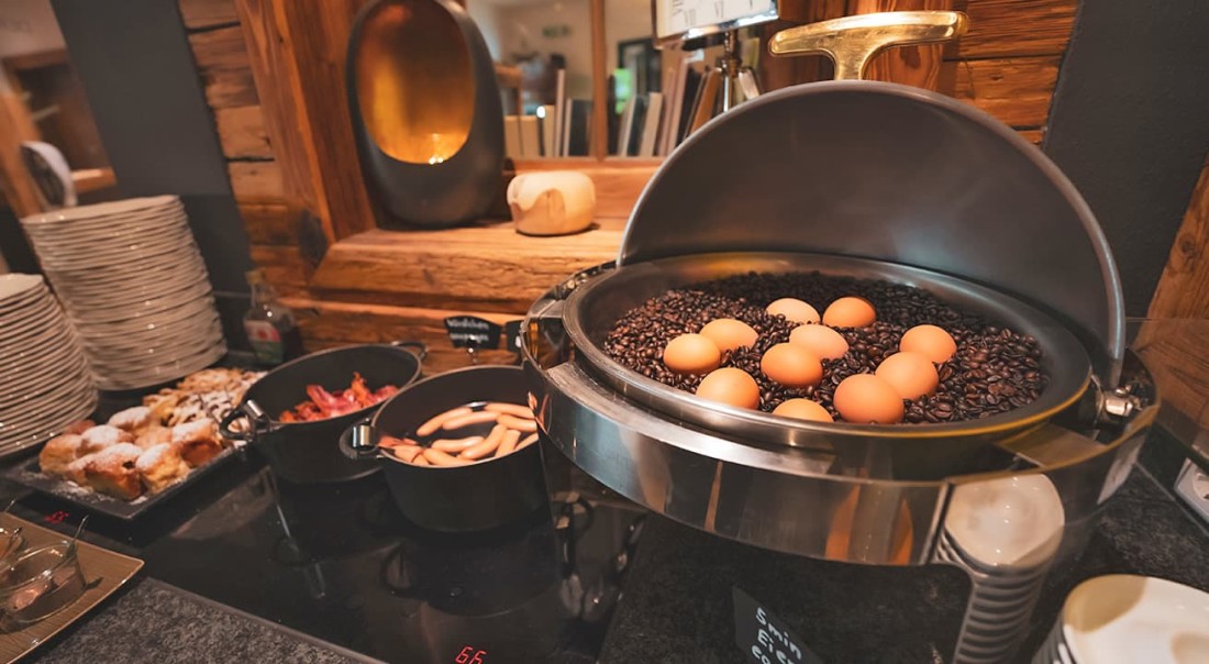 Eier liegen auf Kaffeebohnen in einem Fr&uuml;hst&uuml;cksbuffet mit W&uuml;rstchen und Geb&auml;ck