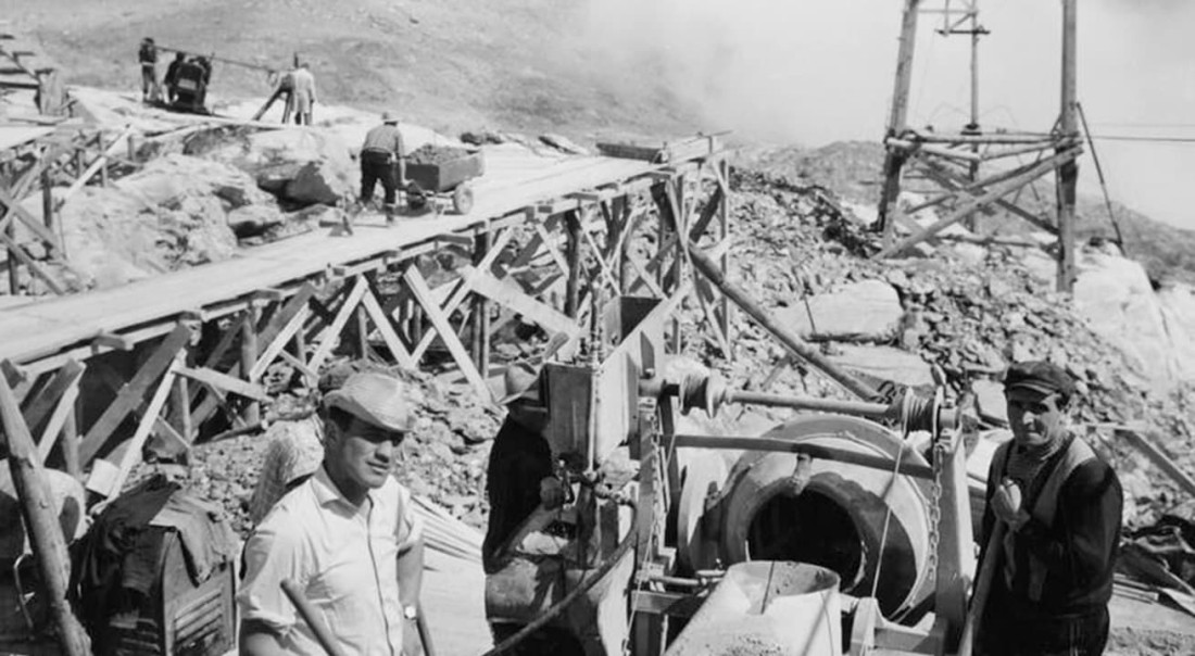 Arbeiter auf einer Baustelle in bergiger Landschaft mit Holzger&uuml;sten und Maschinen beim Bau des Gletscherskigebiets am Kitzsteinhorn