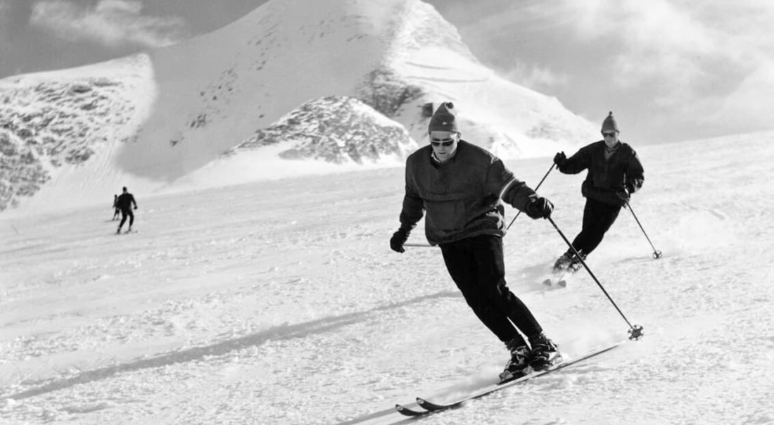 Drei Personen fahren auf Skiern einen verschneiten Hang im Gletscherskigebiet am Kitzsteinhorn hinunter