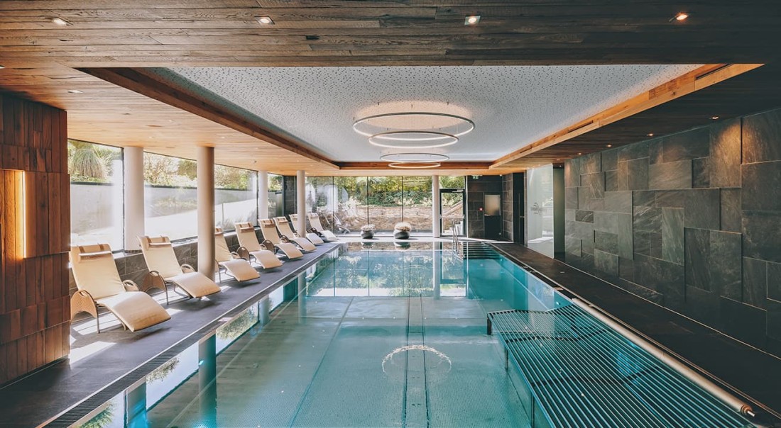 Hallenbad mit modernen Holzdecken und Liegest&uuml;hlen am Rand im Hotel Kaprunerhof
