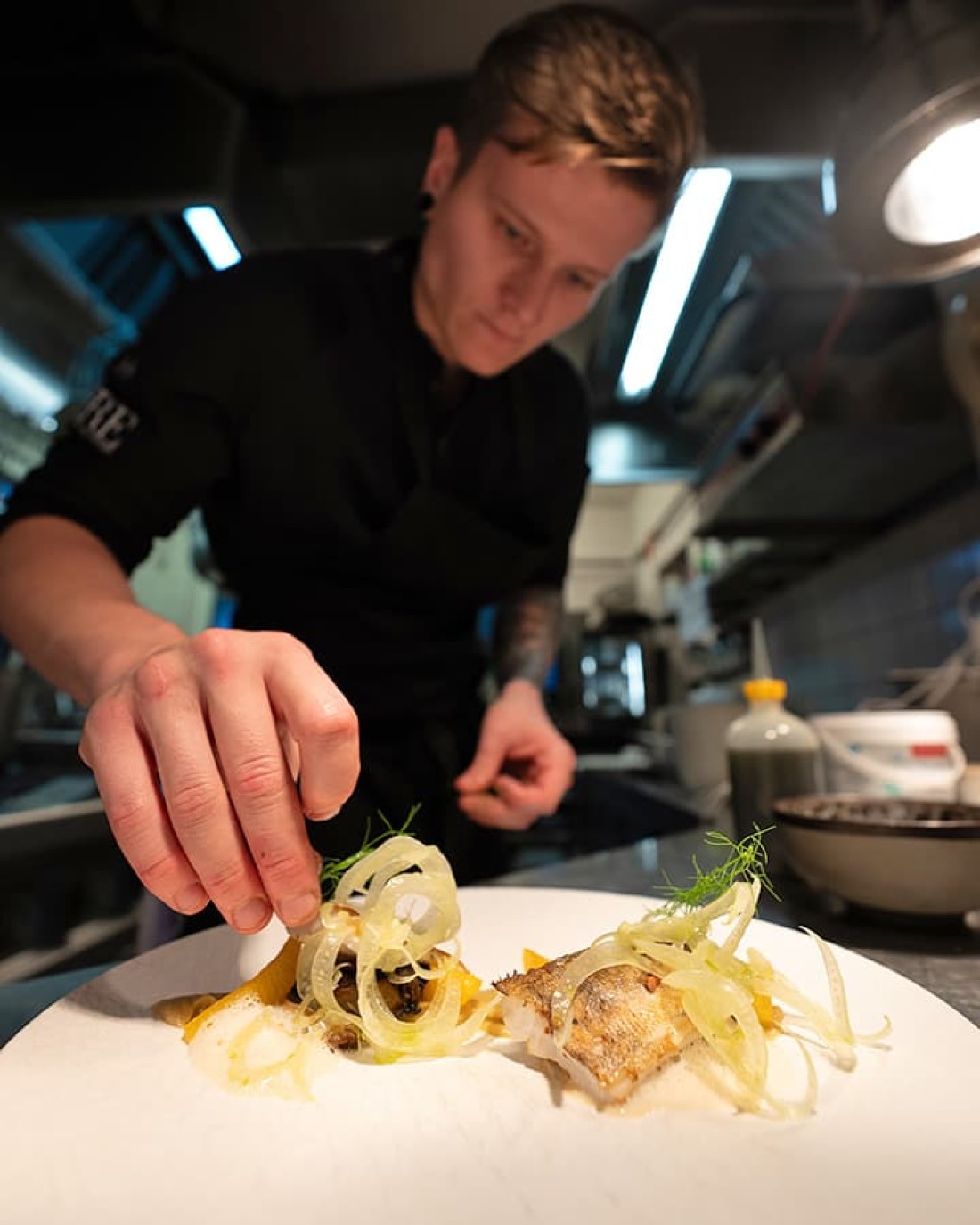 K&uuml;chenchef Stefan Unterkofler dekoriert Teller mit Fisch und Gem&uuml;se in einer modernen Restaurantk&uuml;che