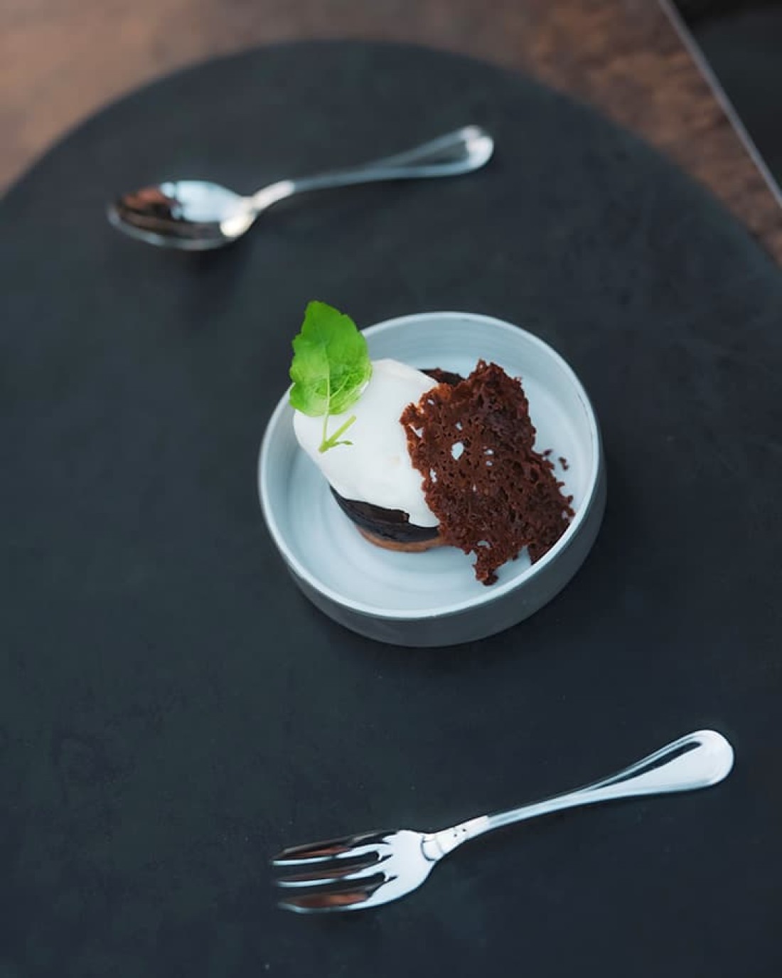 Dessert mit Sahne, Schokolade und Minze in einer Schale, mit zwei Gabeln daneben