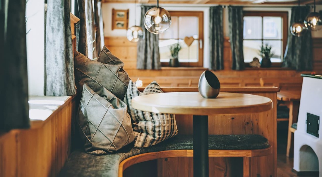Ofenstube mit runden Tisch, Kissen und Pendelleuchten in der Ofenstube im Hotel Kaprunerhof