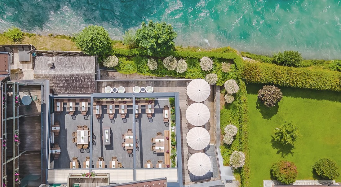 Au&szlig;enbereich von der Sonnenterrasse am Wasser mit Tischen und gro&szlig;en Sonnenschirmen im Hotel Kaprunerhof im Hotel Kaprunerhof