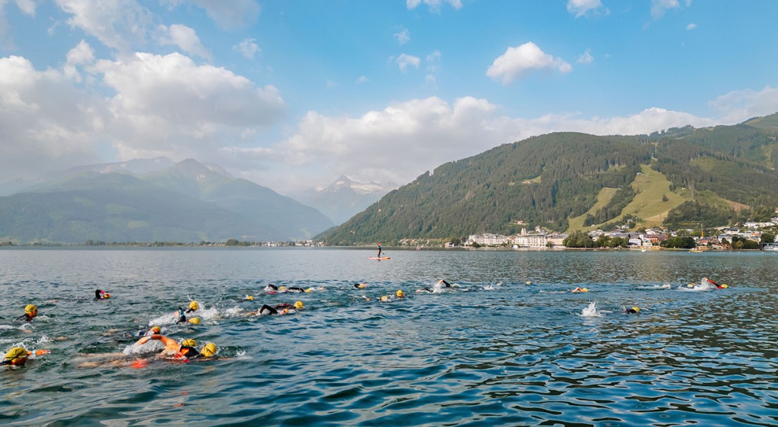 Triathleten schwimmen im Zeller See See vor einer malerischen Bergkulisse