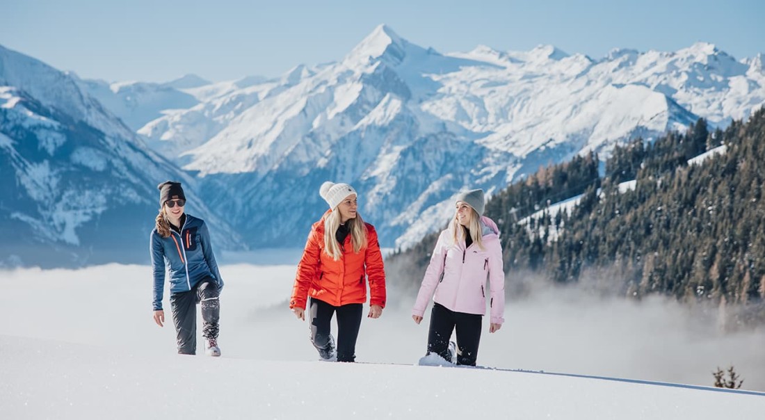Drei Frauen wandern durch schneebedeckte Berge bei klarem Wetter