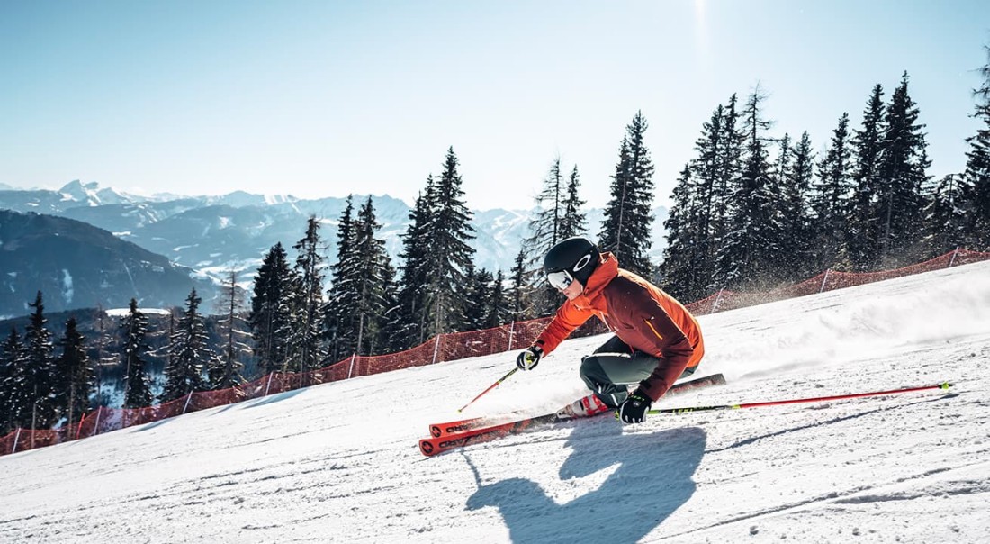 Eine Person f&auml;hrt auf Skiern eine schneebedeckte Piste auf der Schmittenh&ouml;he hinunter
