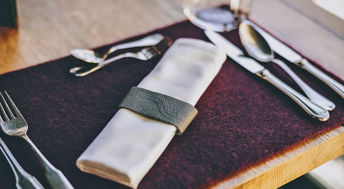 Zusammengelegte Serviette mit Besteck auf einem Tischset