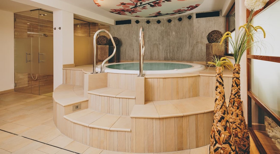 Moderner Wellnessbereich mit rundem Whirlpool und dekorativen Pflanzen im Hotel Kaprunerhof