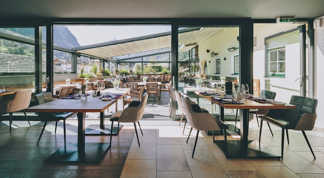Helle Restaurantterrasse mit Bergblick und eingedeckten Tischen aus Holz im Hotel Kaprunerhof