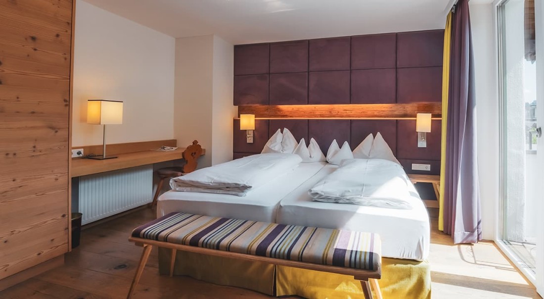 Helles Schlafzimmer mit Doppelbett, Holzm&ouml;beln und Leselampen