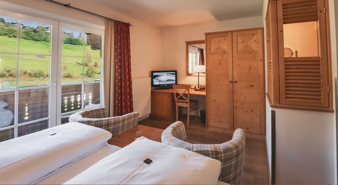 Gem&uuml;tliches Zimmer mit Blick auf eine gr&uuml;ne Wiese durch ein gro&szlig;es Fenster