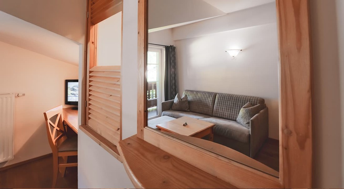 Ein Zimmer mit Sofa, Tisch und einem kleinen Arbeitsbereich mit TV