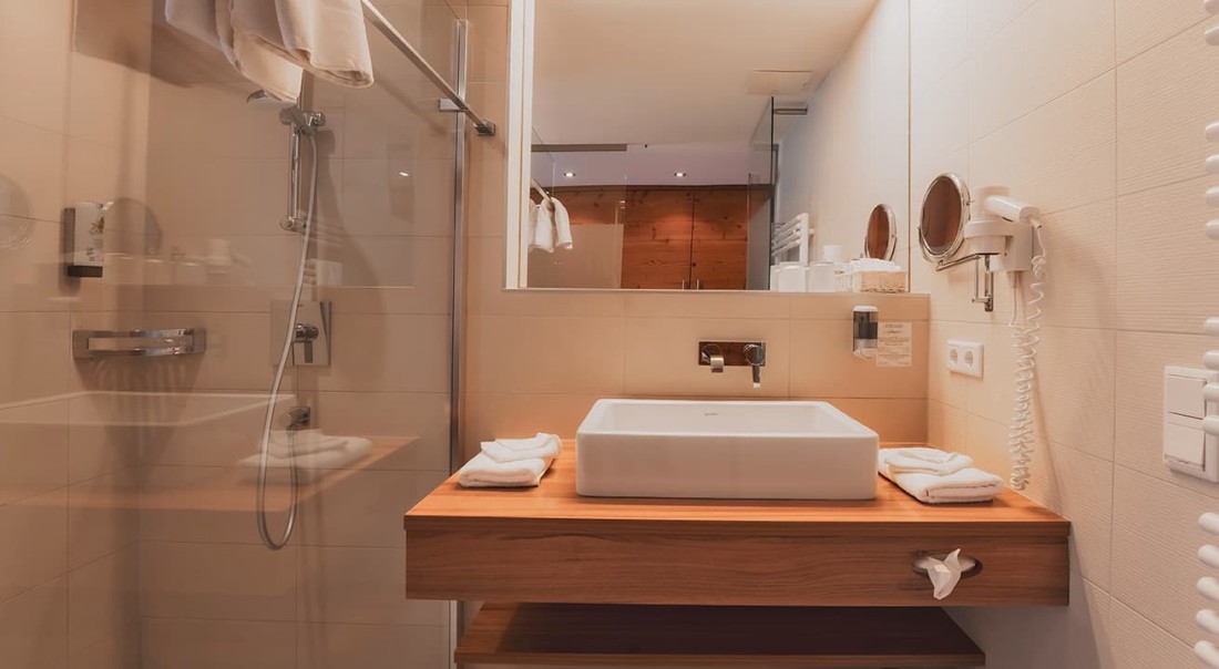 Modernes Badezimmer mit Holzwaschtisch und Glasdusche
