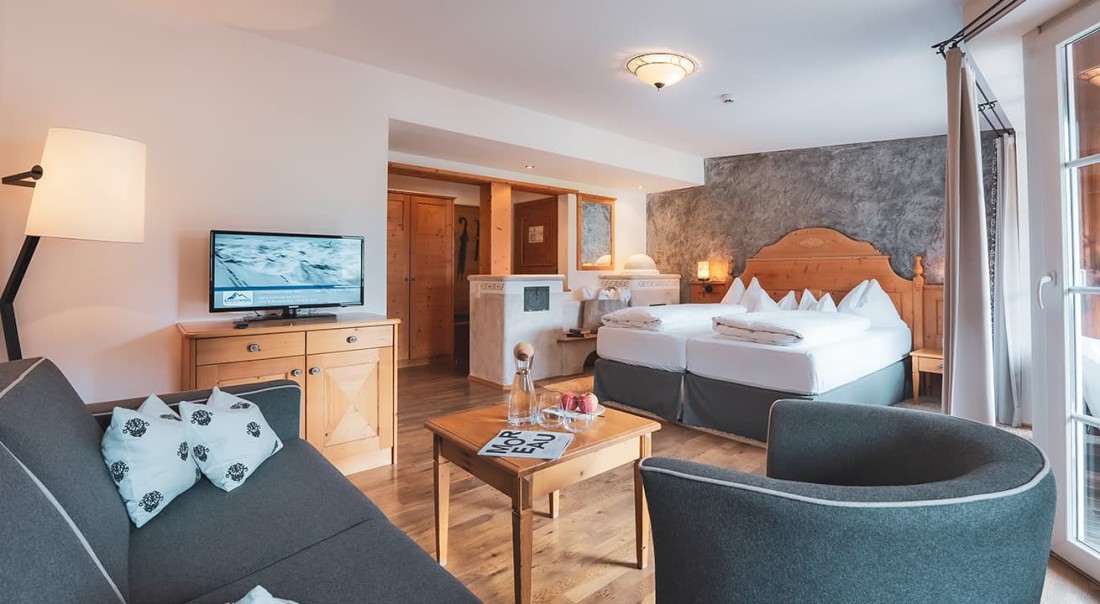 Ger&auml;umiges Hotelzimmer mit Doppelbett, Sofa, Fernseher und Holzm&ouml;beln