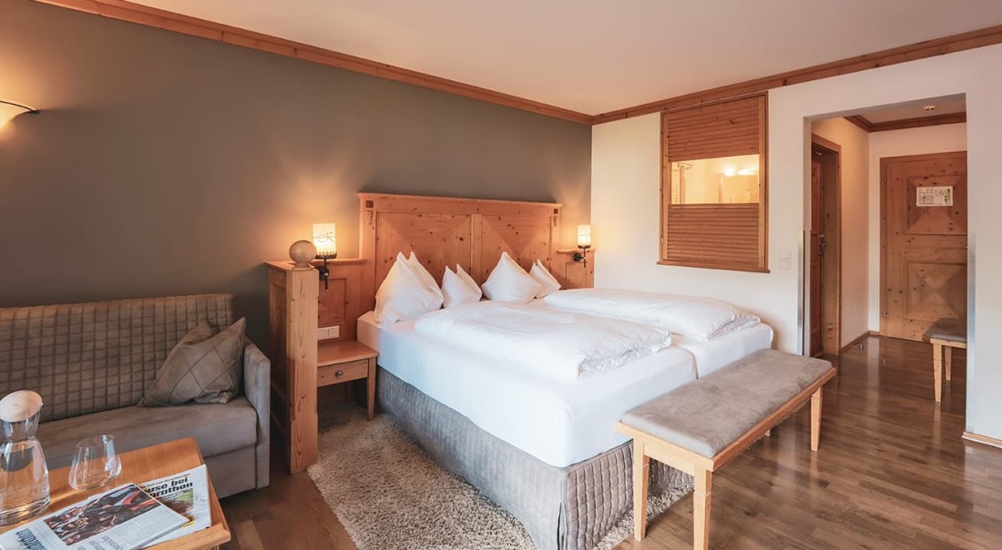 Gem&uuml;tliches Hotelzimmer mit Doppelbett, Sofa, Holzm&ouml;beln und heller Beleuchtung