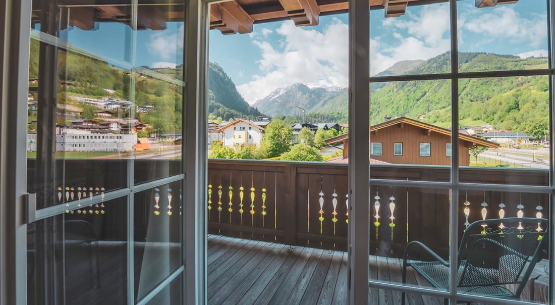 Blick vom Balkon auf Alpenlandschaft mit blauem Himmel und Holzh&auml;usern