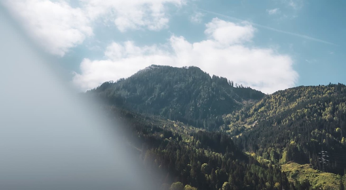 Ein bewaldeter Berg unter blauem Himmel mit einigen Wolken