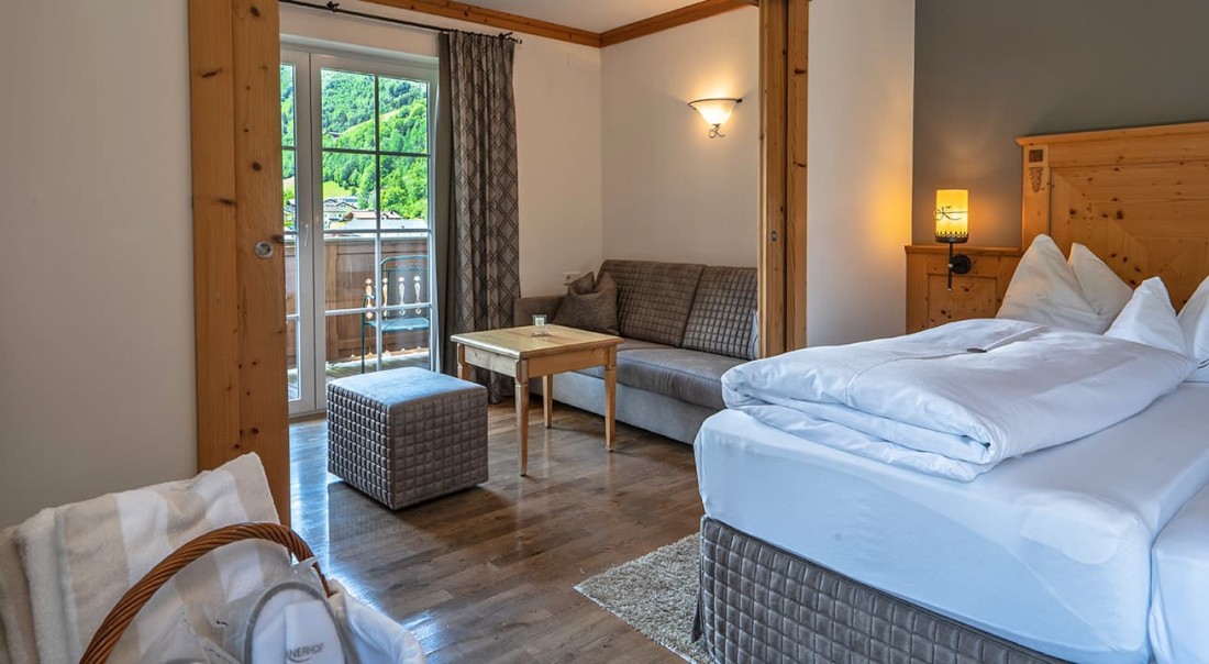 Helles Hotelzimmer mit Balkon und Bergblick, ausgestattet mit Sofa und Doppelbett